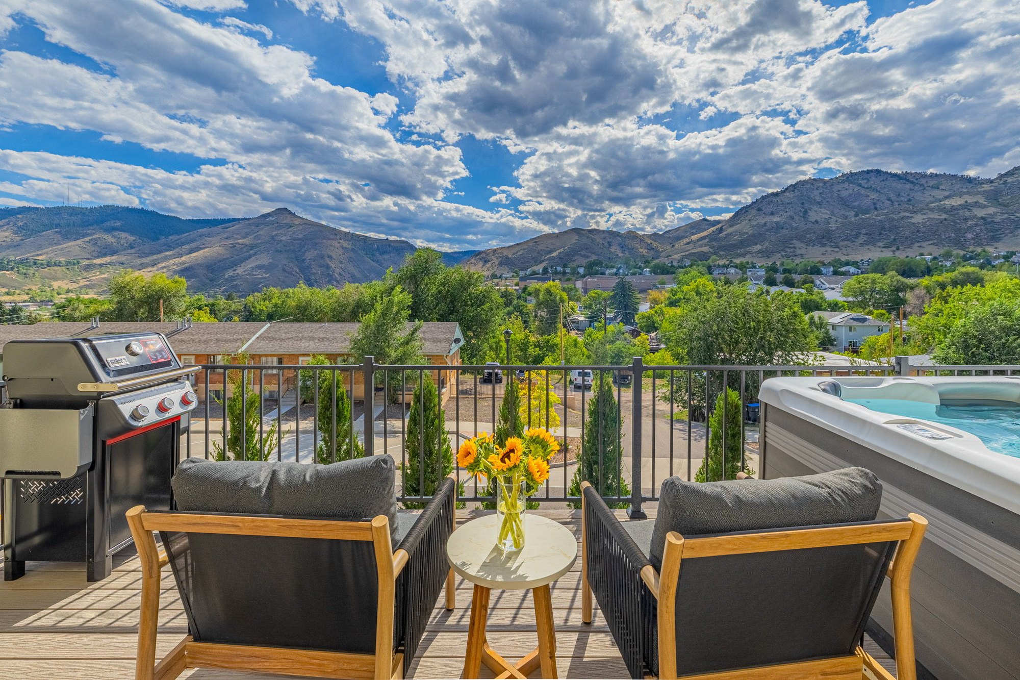Deck seating area with a grill and hot tub overlooking the Golden foothills