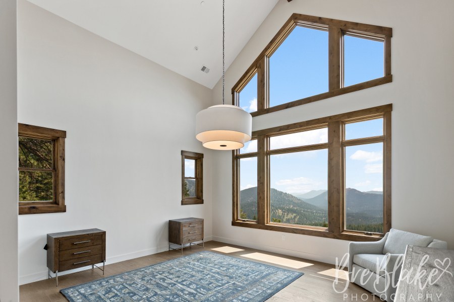 Vaulted primary bedroom with wood-trimmed windows framing the foothills
