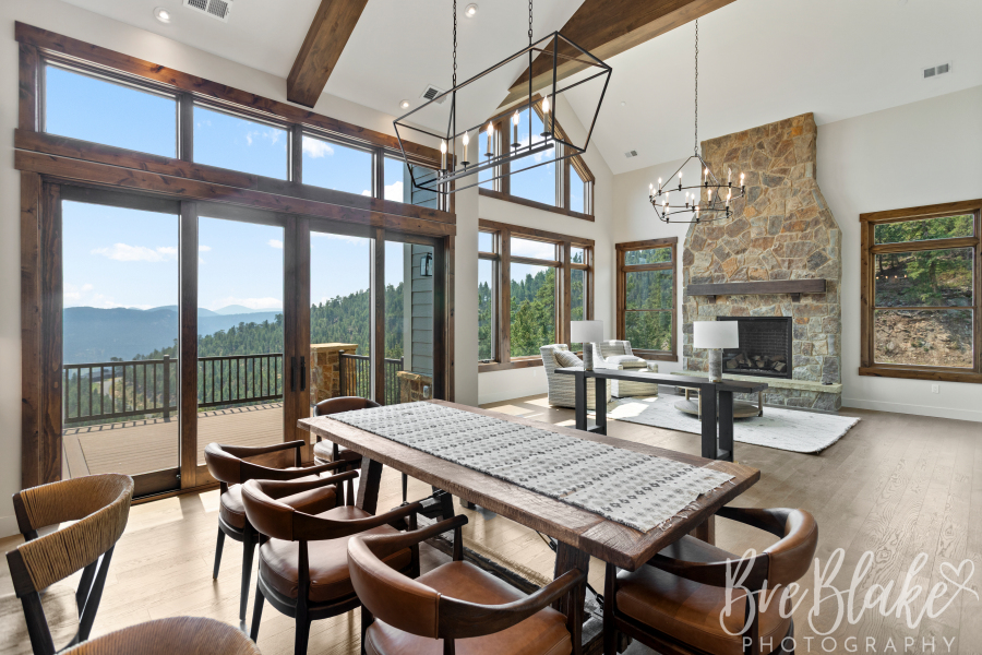 Vaulted great room with a stone fireplace, exposed beams and floor-to-ceiling foothills views