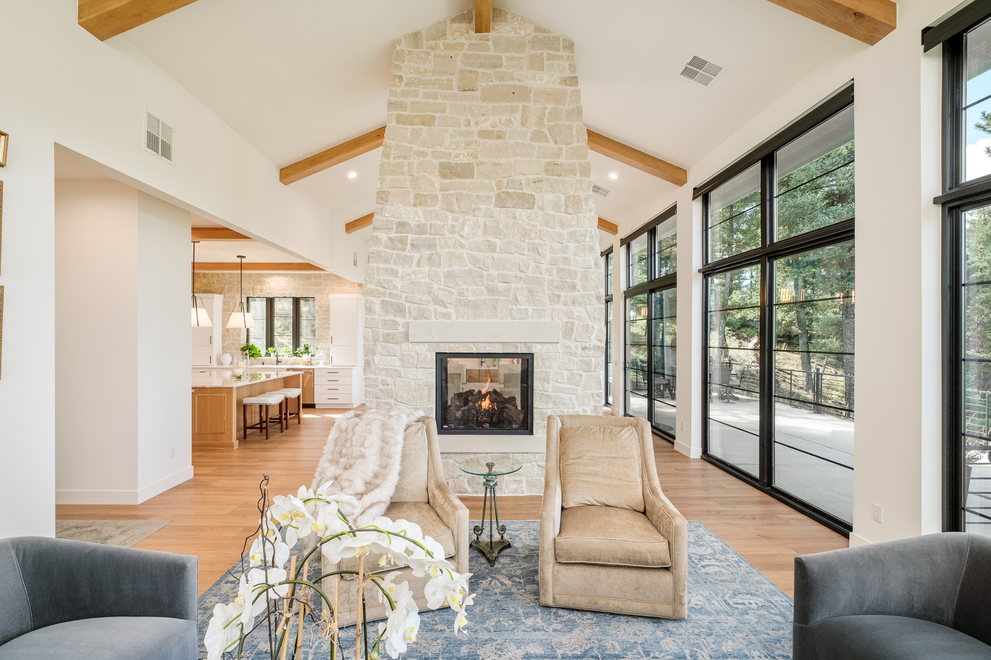 Vaulted living room with a two-sided stone fireplace and mountain-facing windows