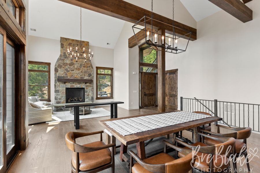 Open dining and entry area with a stone fireplace, exposed beams and steel stair railing