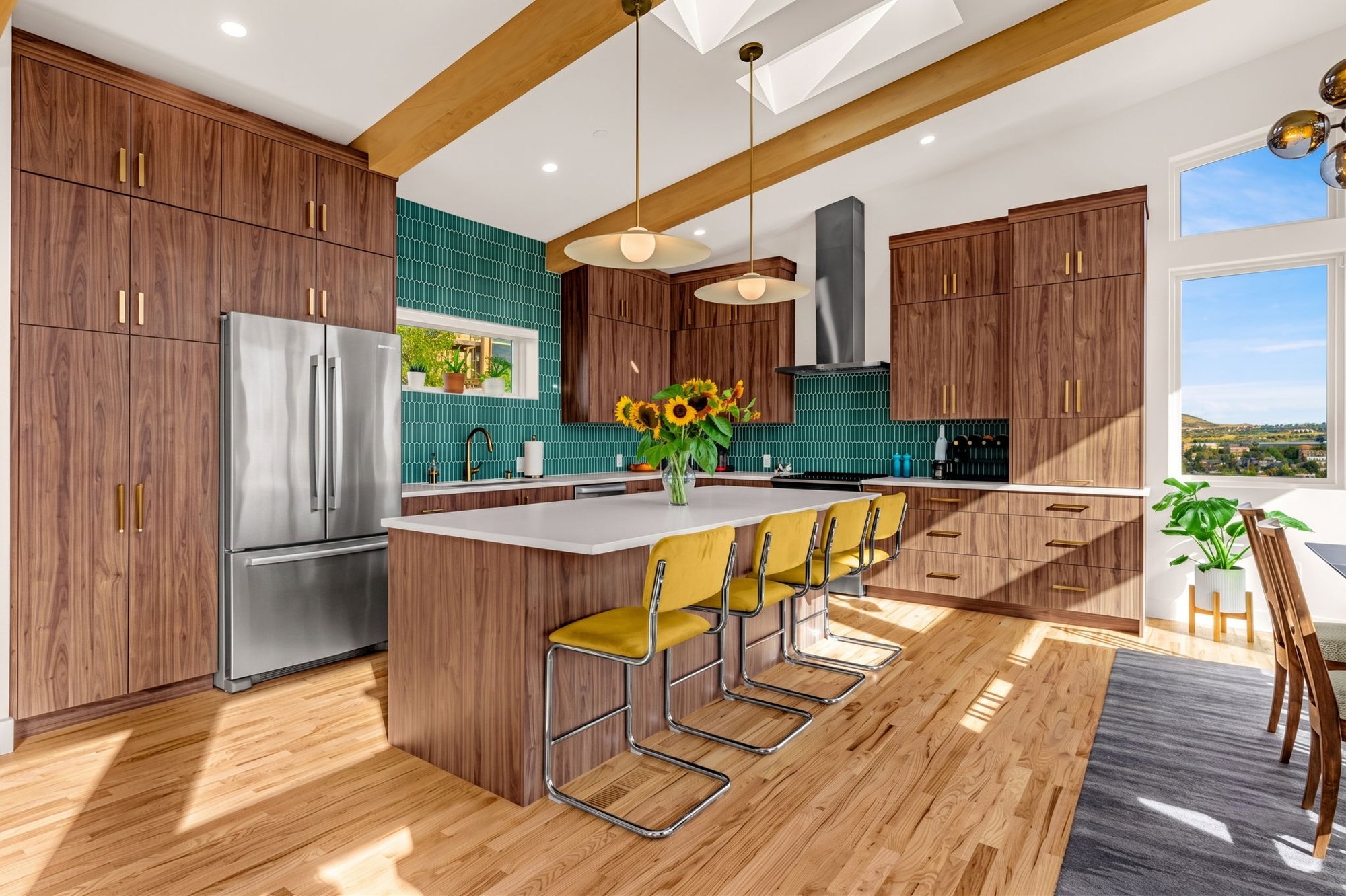 Full view of the walnut kitchen with skylights, beams and a teal tile backsplash
