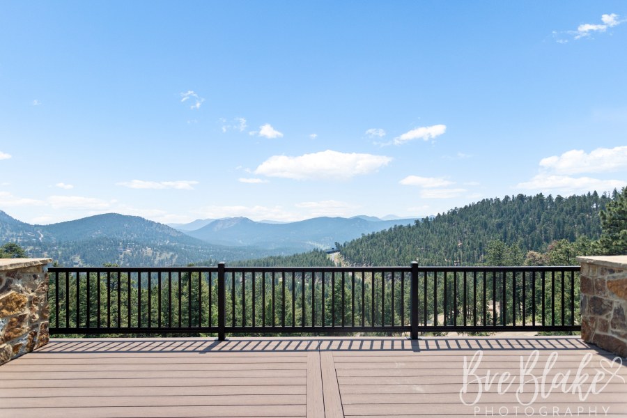 Deck between stone pillars with a steel railing and panoramic foothills views