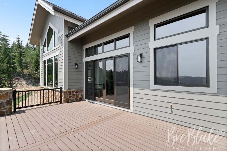 Composite deck with French doors, transom windows and gray lap siding