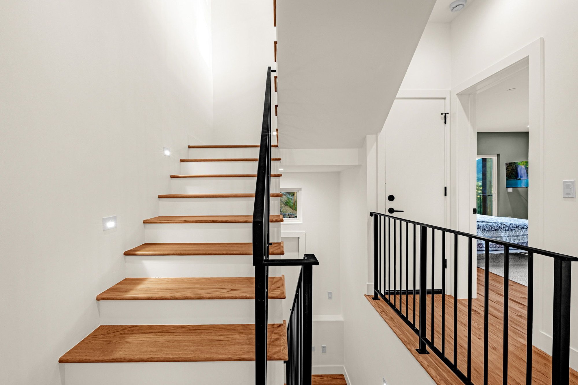Open-riser stair in white oak with a black steel balustrade