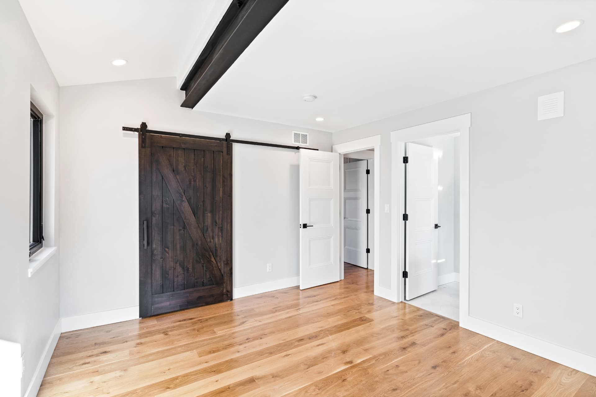 Bedroom with barn door to the ensuite bath and white oak flooring