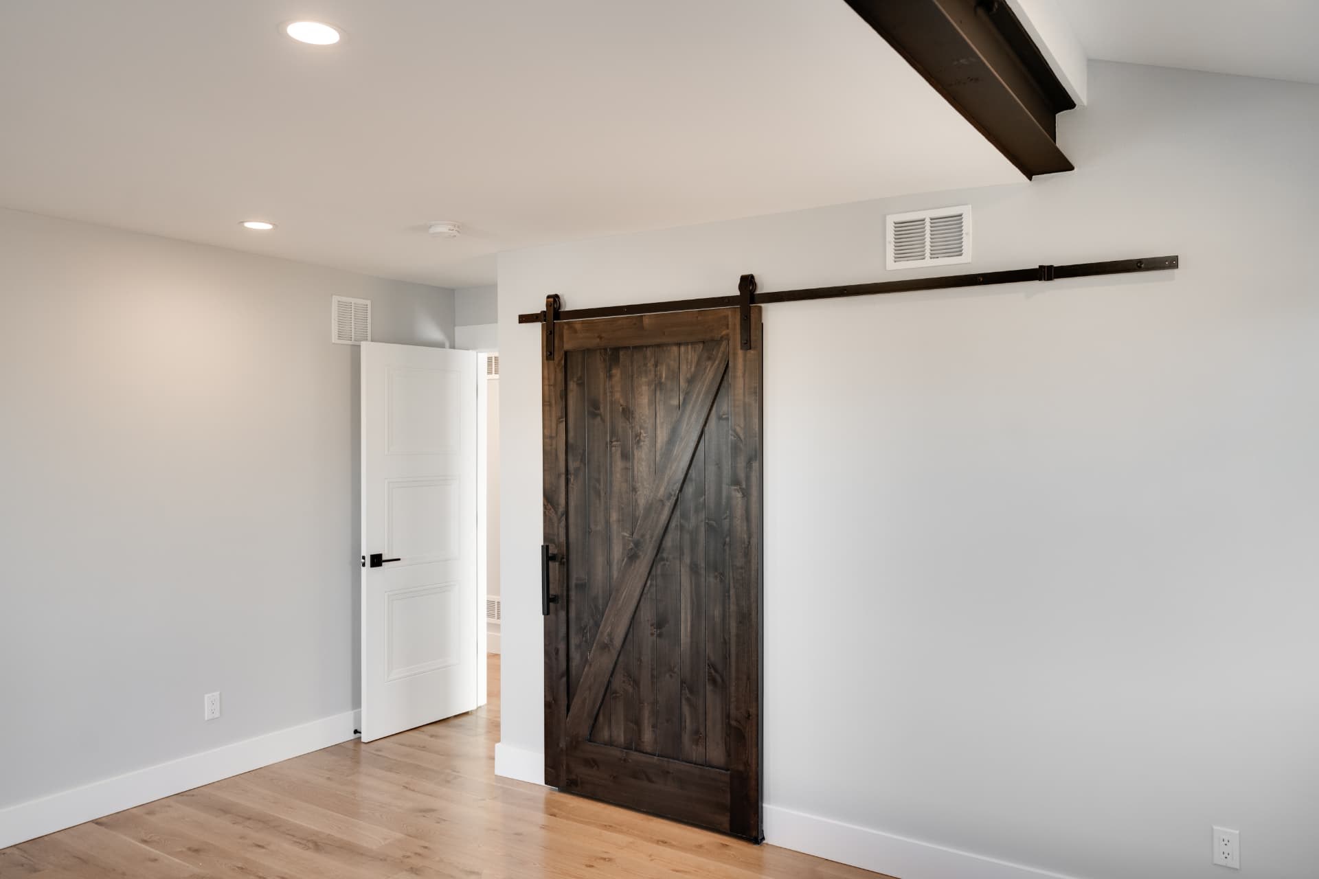 Hallway with a sliding barn door beneath an exposed steel beam