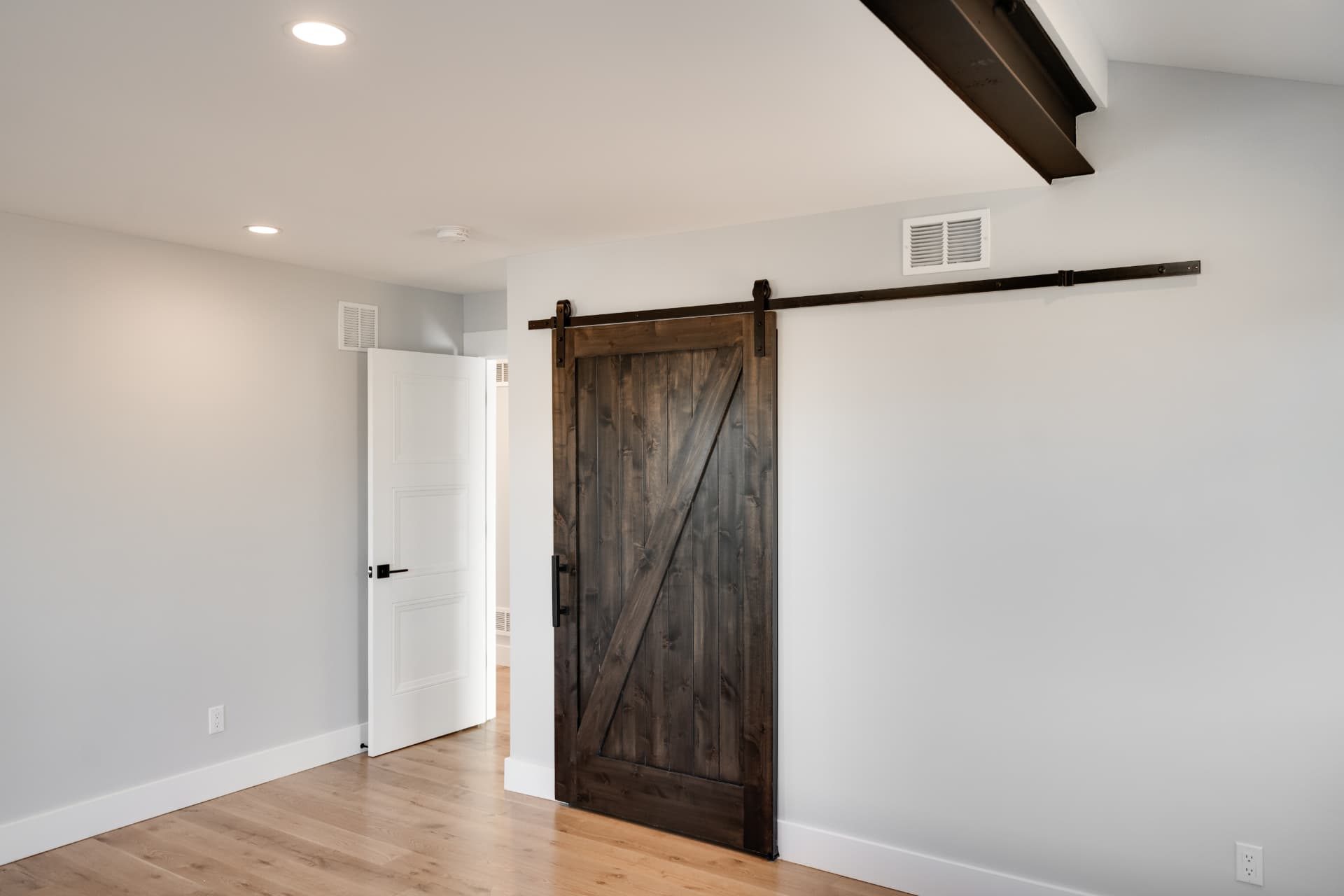 Bedroom with barn door and exposed steel beam across the ceiling