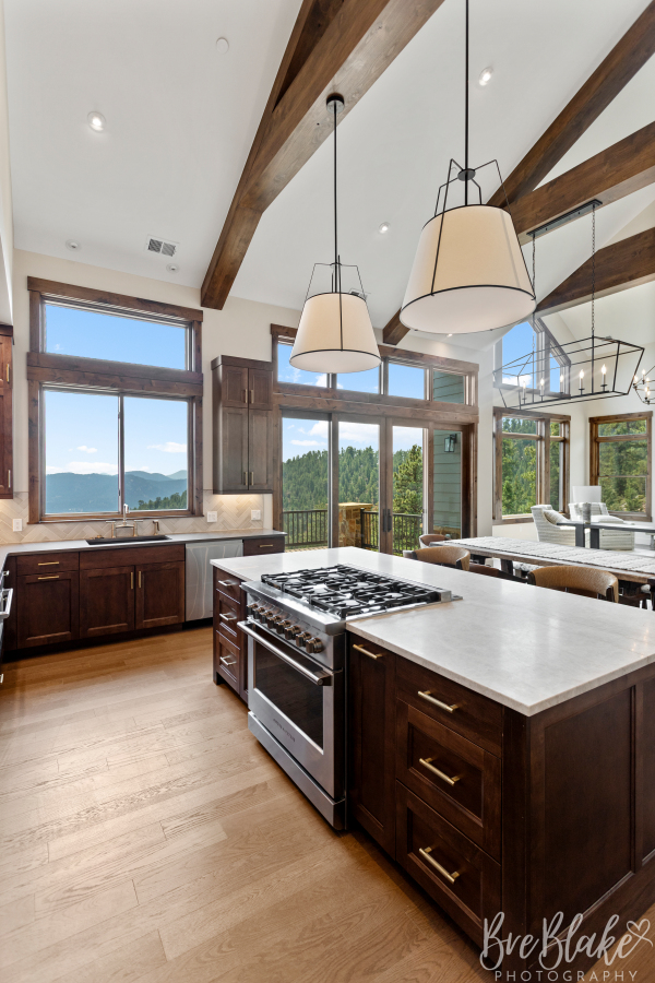 Vaulted kitchen with exposed beams, dark wood cabinetry and foothills views