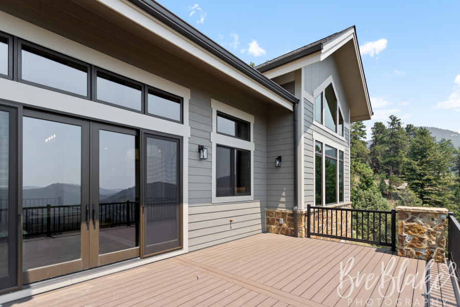 Deck and rear exterior with gray siding, stone columns and mountain views