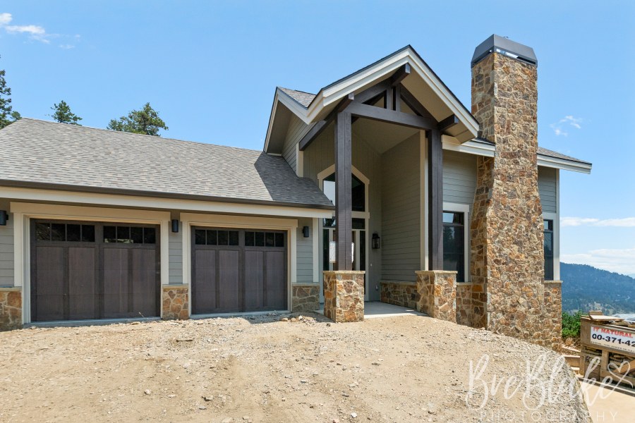 Front exterior with a timber-framed entry, stone chimney and two-car garage