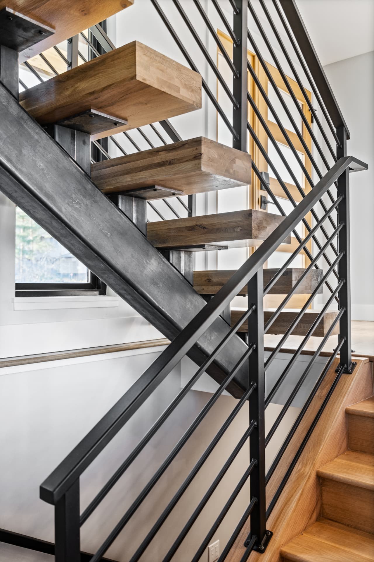 Floating stair with thick wood treads on a blackened steel stringer