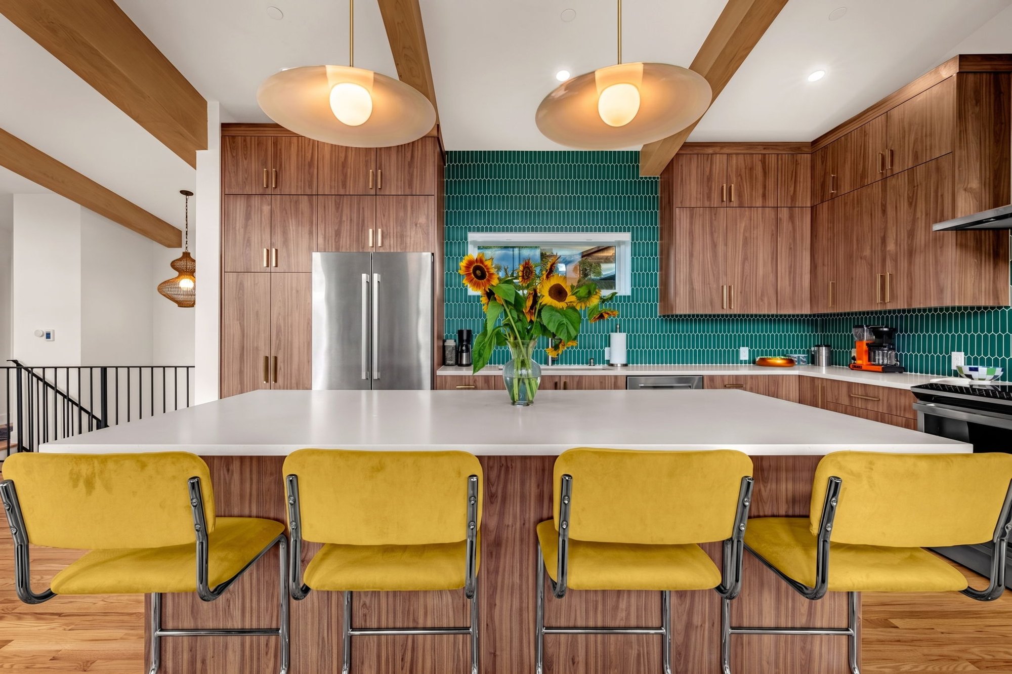 Walnut waterfall island with quartz top beneath twin pendant lights