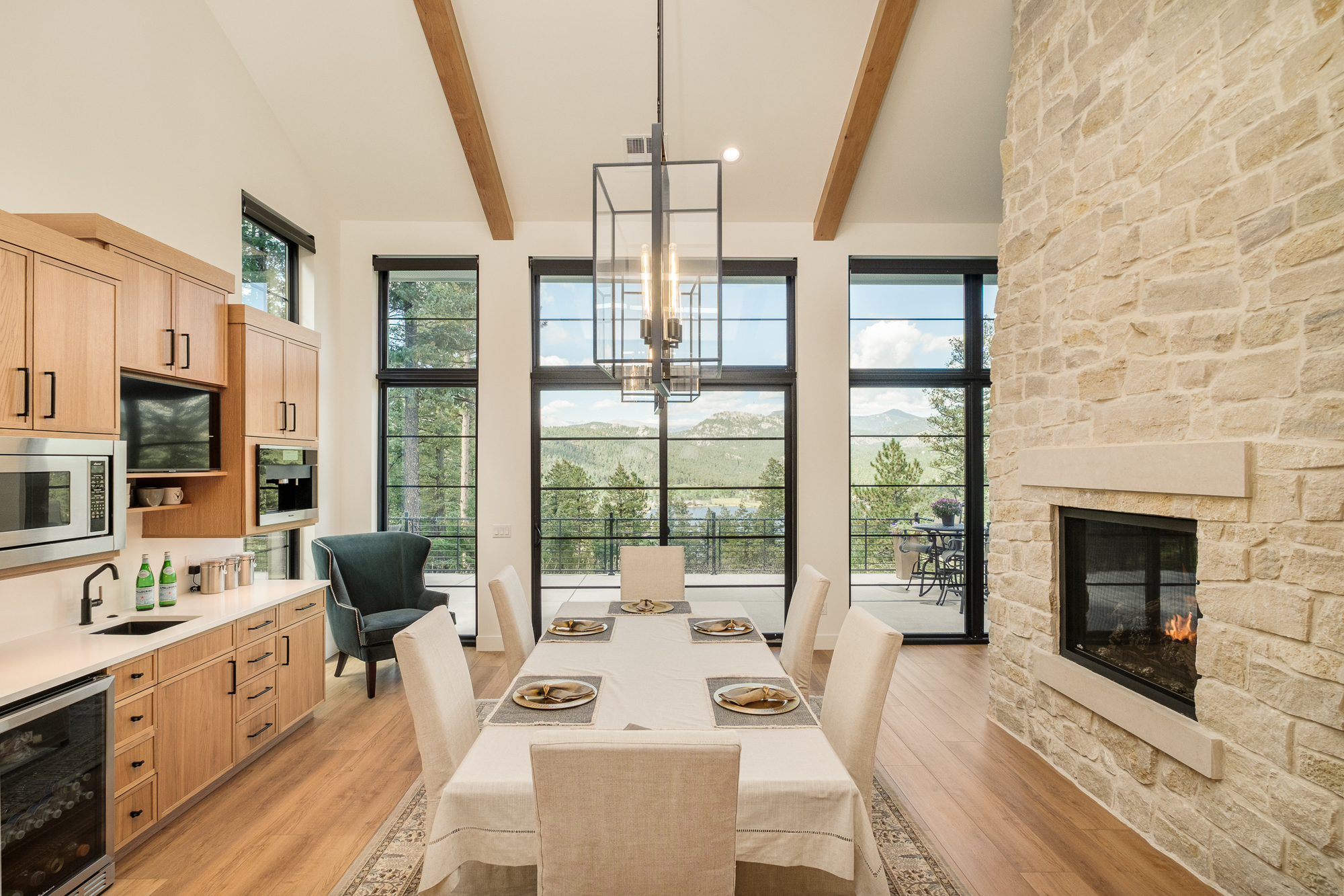 Dining room with mountain views, oak cabinetry and a two-sided stone fireplace
