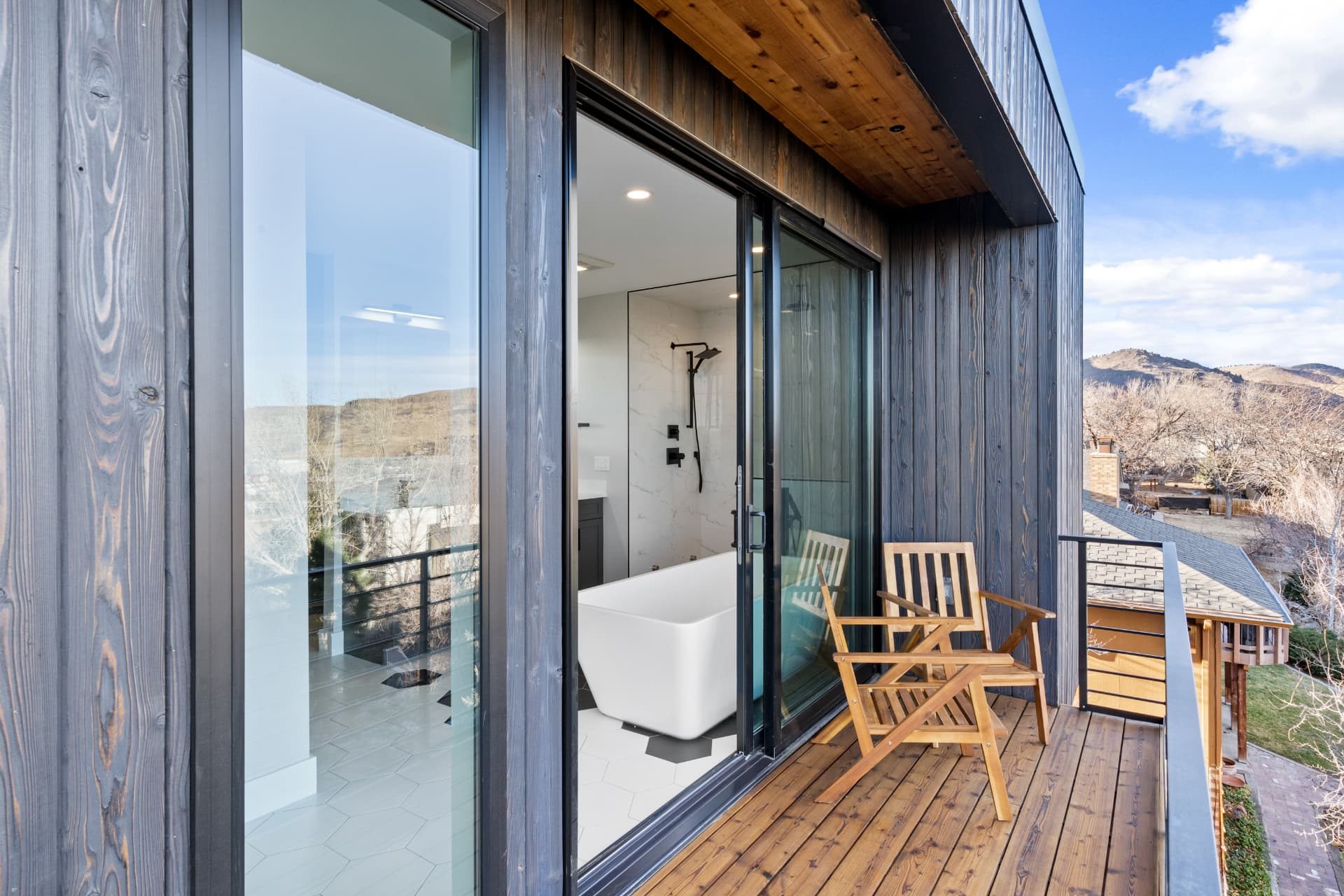 Balcony in dark wood siding with sliding glass doors into the primary bath