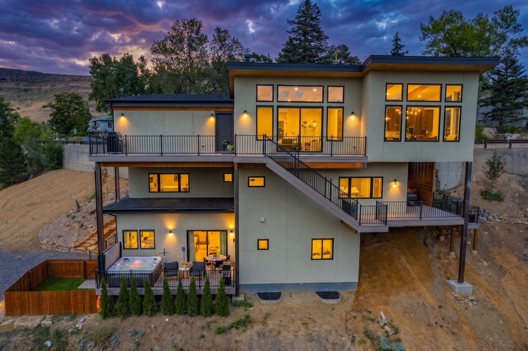 Modern three-story home in Golden, Colorado at dusk, with stacked decks and warm interior lighting