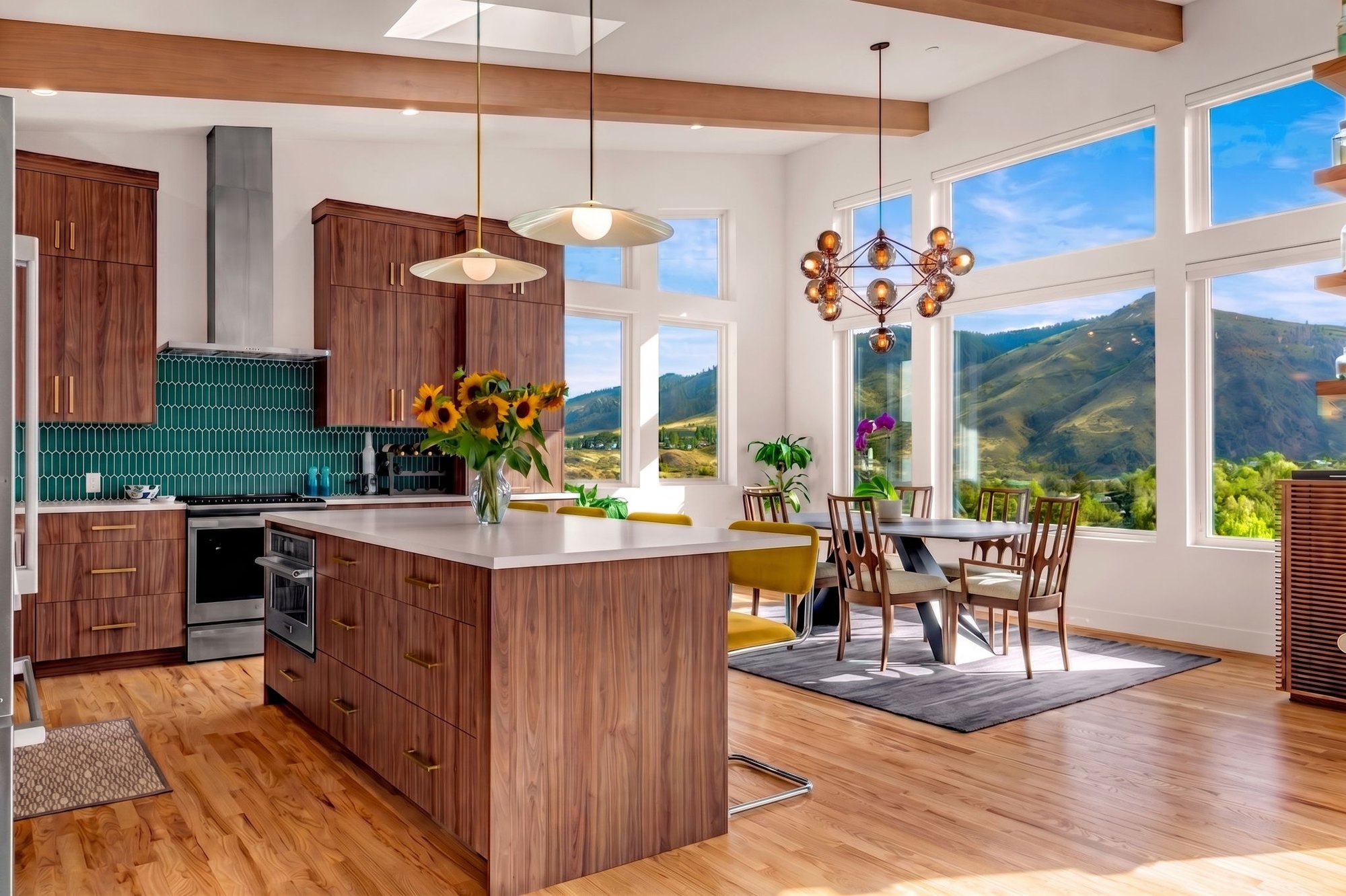 Walnut kitchen with teal picket-tile backsplash opening onto a dining area with mountain views