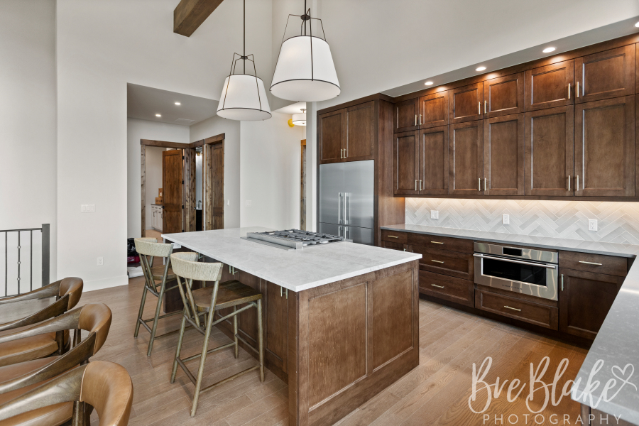 Kitchen with dark wood cabinetry, a stone-topped island and herringbone tile backsplash
