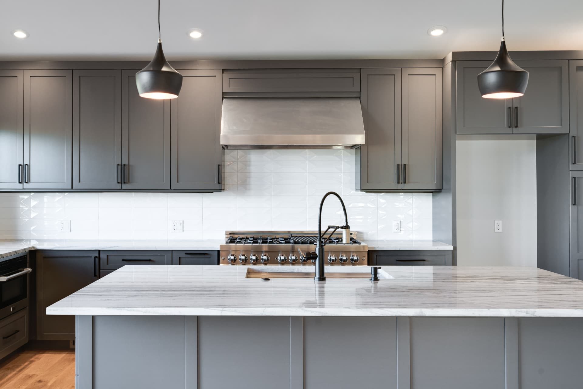 Kitchen range wall with stainless hood and white geometric tile backsplash